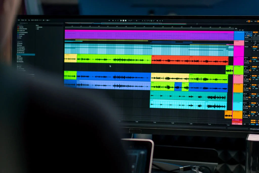 Colour-coded video editing timeline on a dark studio monitor