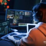 Video editor working late at a multi-screen workstation
