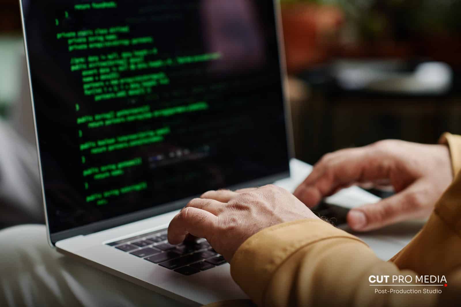 Hands typing code on a laptop with green text on screen